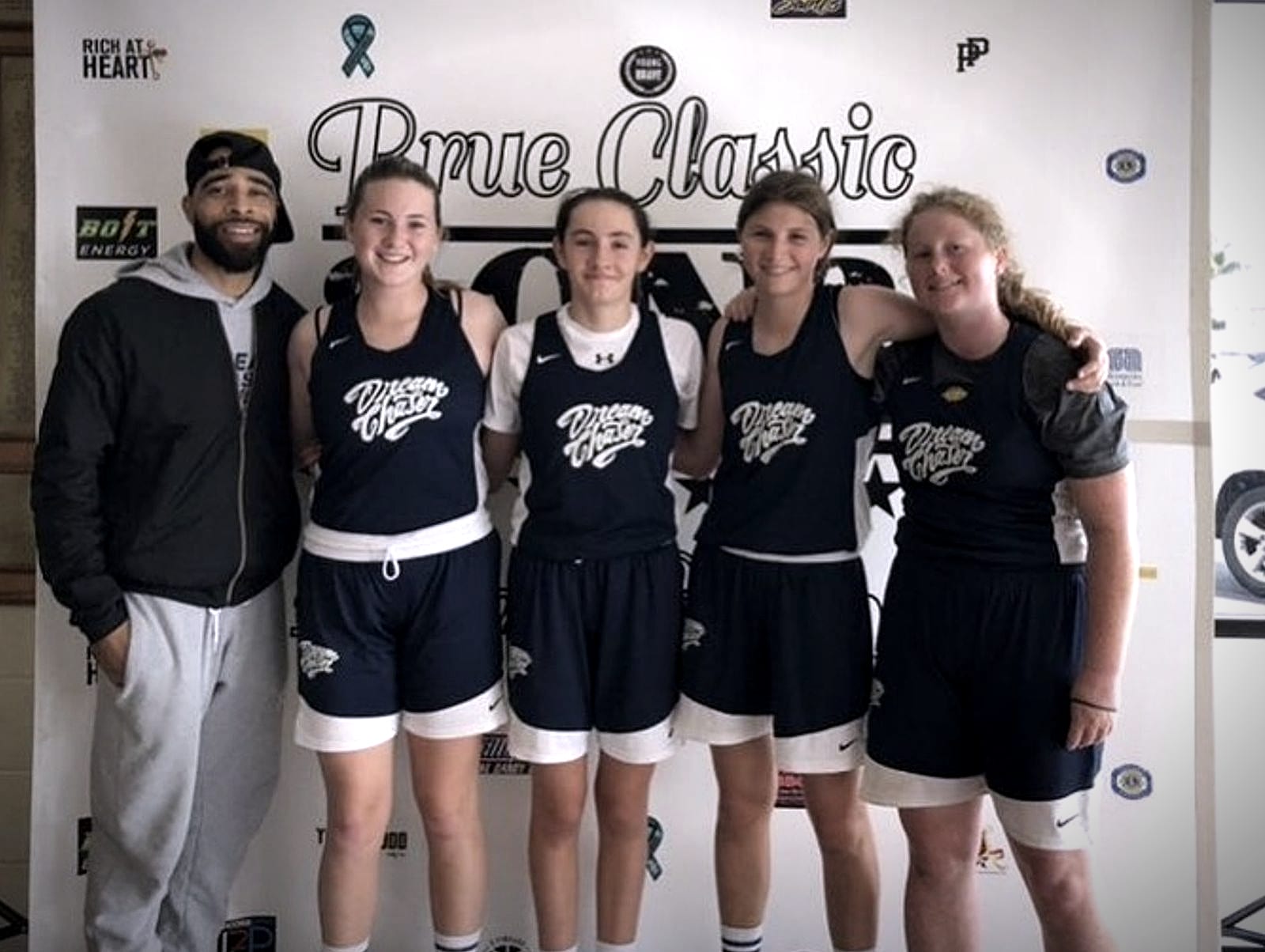 Coach Jelani standing with four Dream Chaser players at a tournament